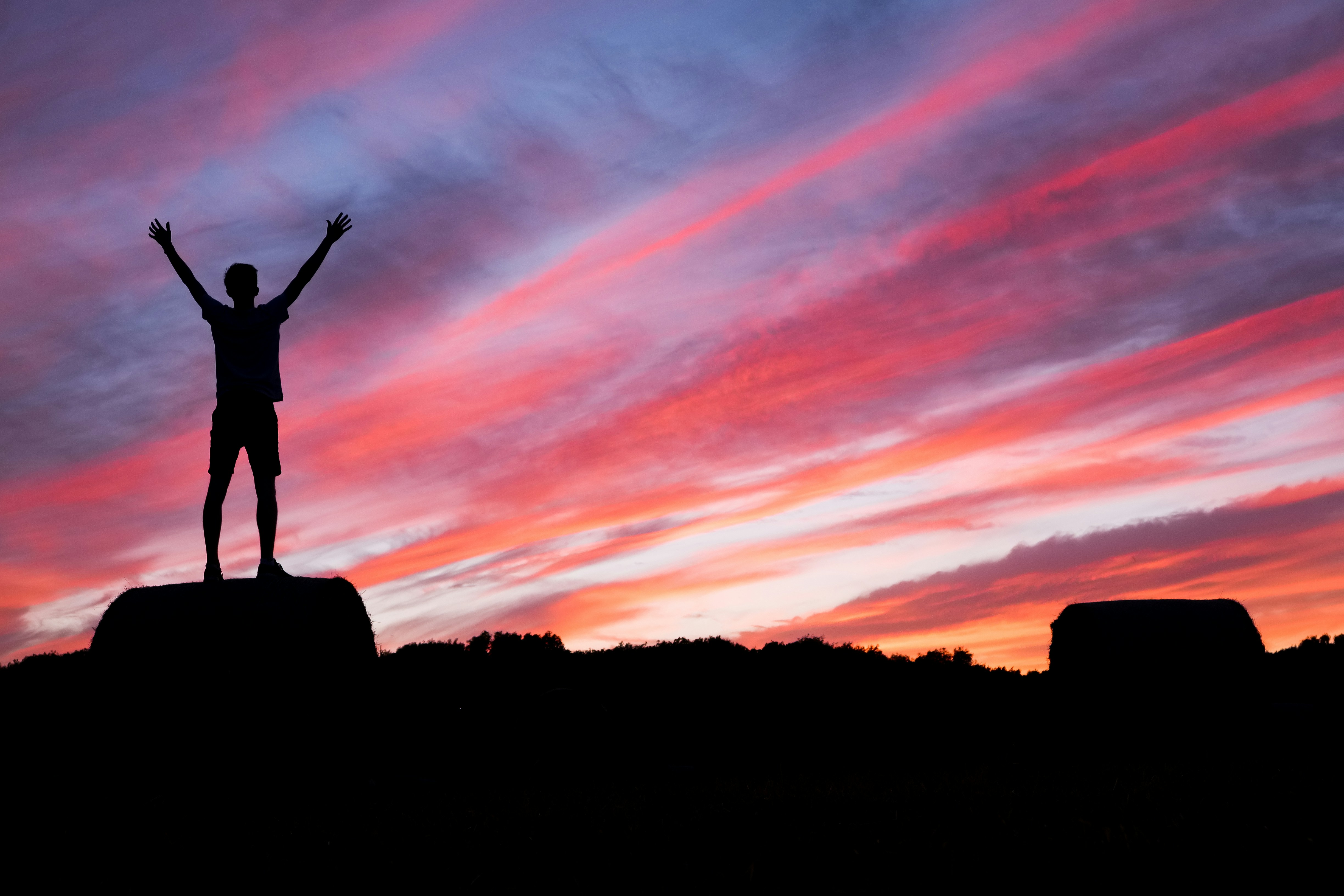 Silhouette of a person at sunset under red and blue skies